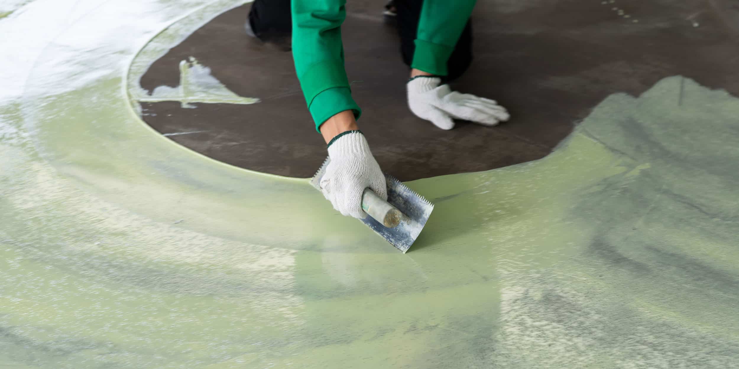 Installer working a green metallic epoxy floor by hand