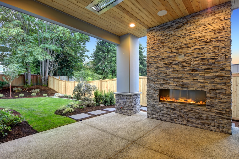 Covered patio with a stone fireplace and a coated concrete floor