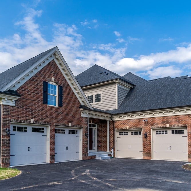 Brick house with three-car garage and blue sky.