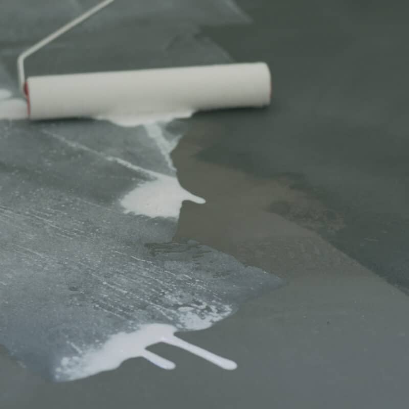 Applying white paint on a dark surface with roller.