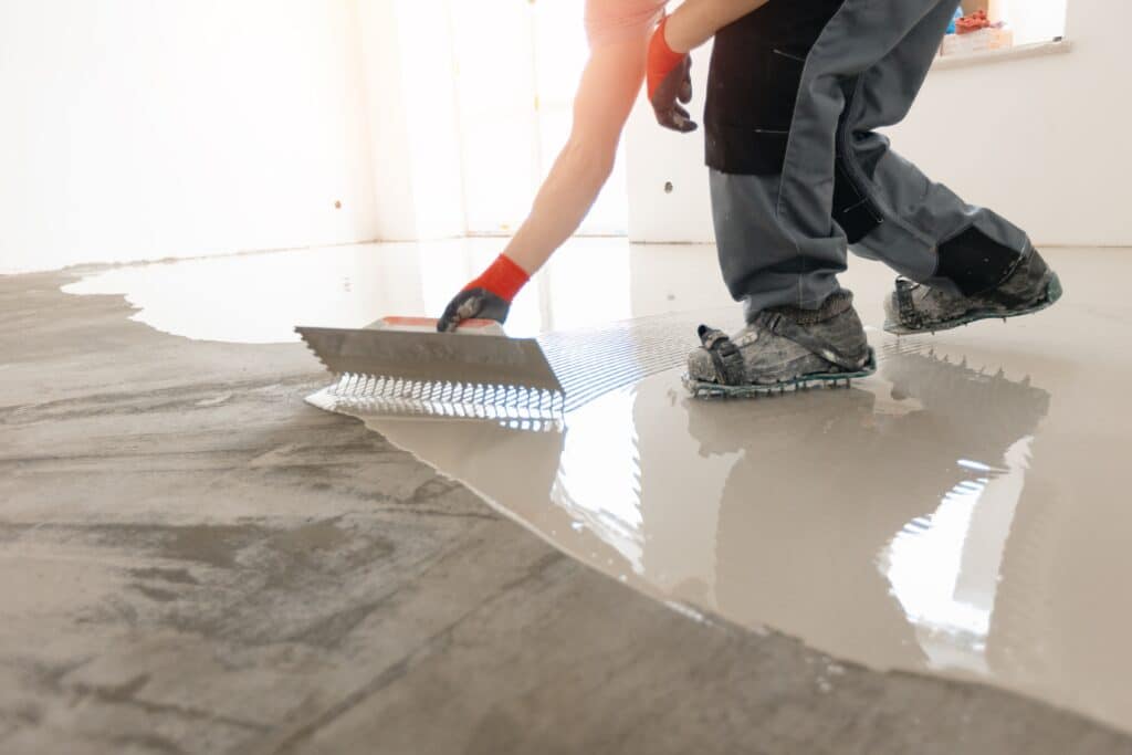 Worker leveling fresh concrete floor.