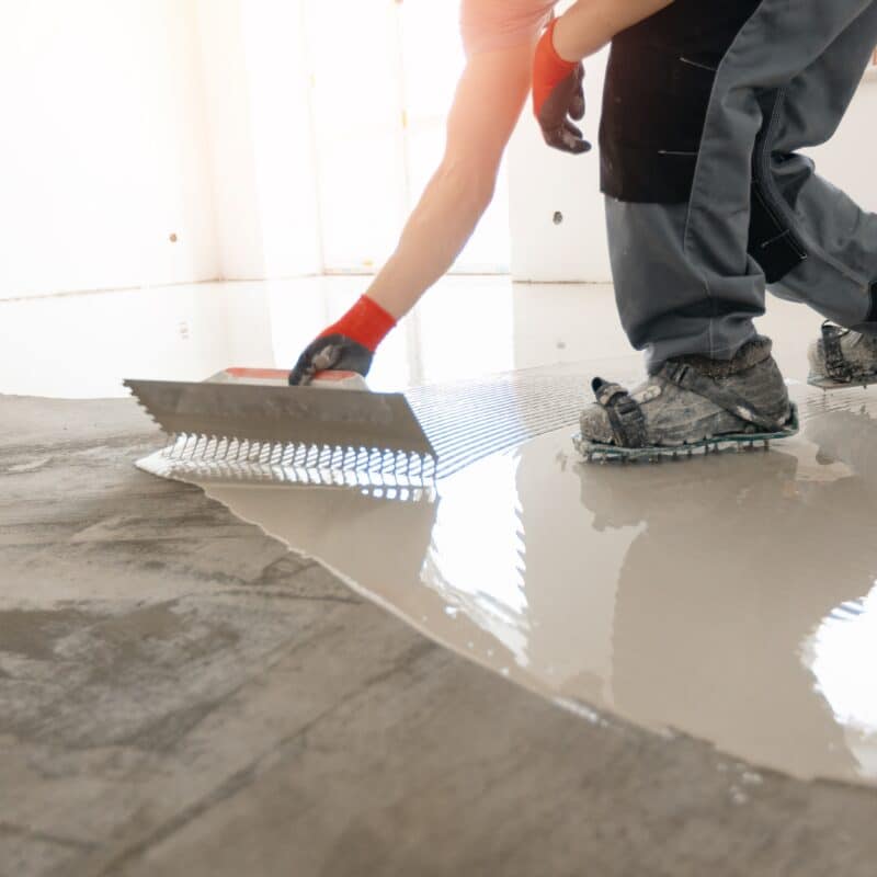 Worker leveling fresh concrete floor.
