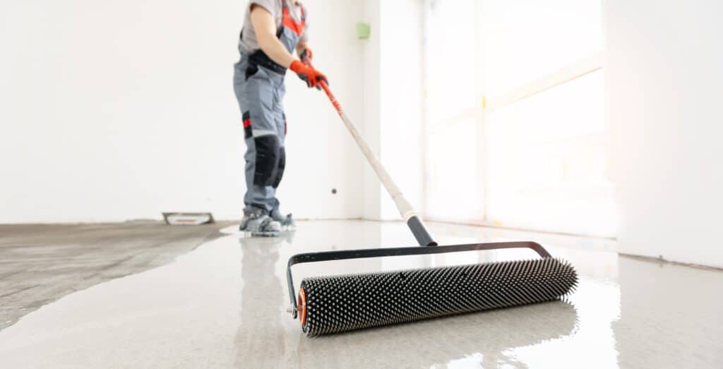 Worker applying epoxy floor coating with roller.