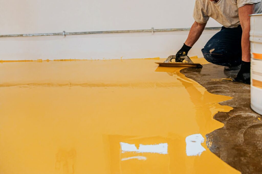 Person applying yellow epoxy floor coating