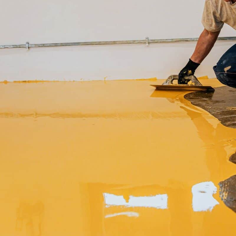 Person applying yellow epoxy floor coating