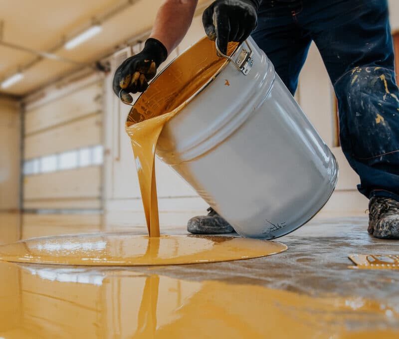 Person pouring yellow paint on floor