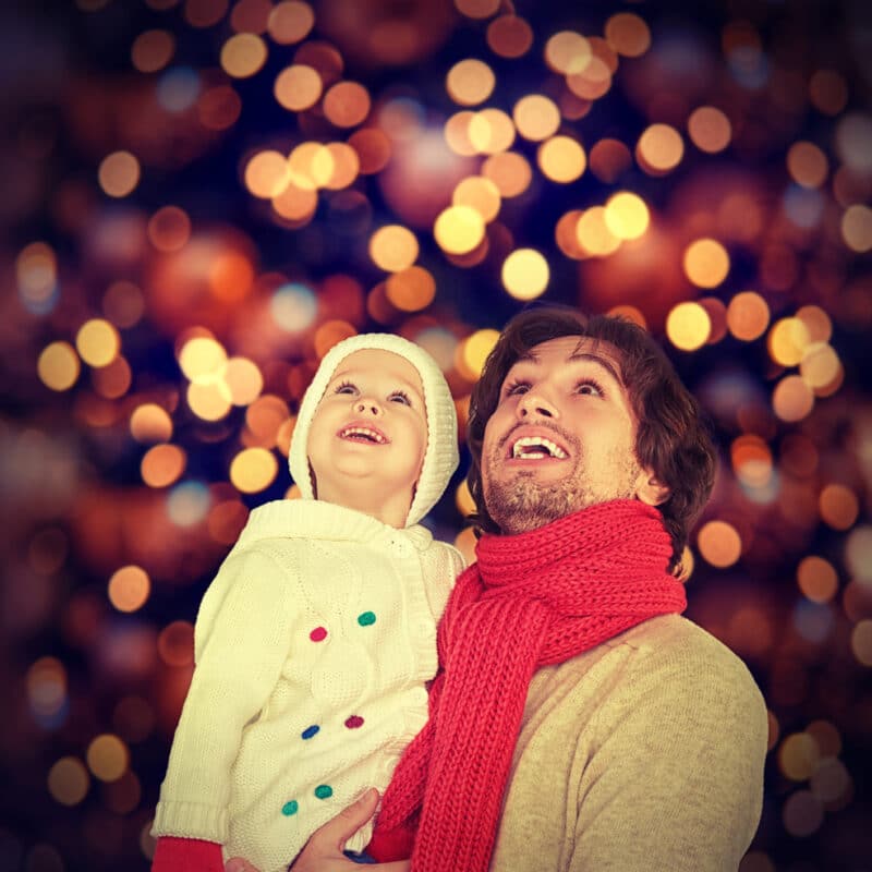Smiling family in winter clothes under festive lights.