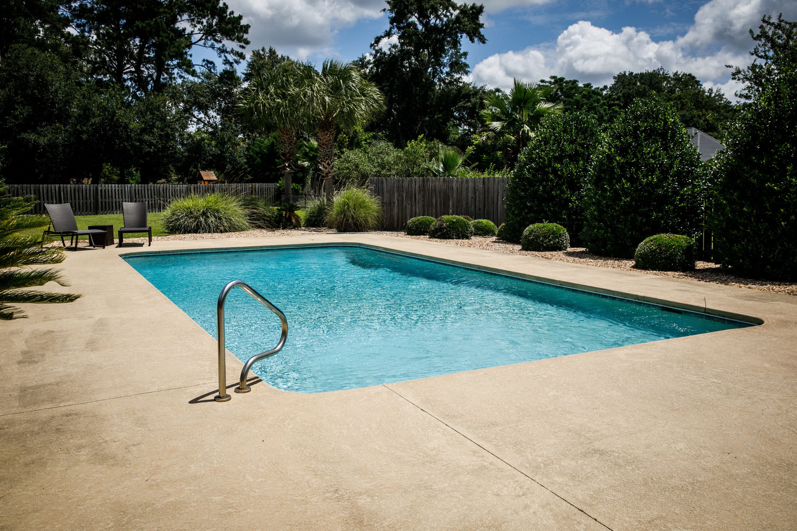Sunny backyard pool with lounge chairs and trees