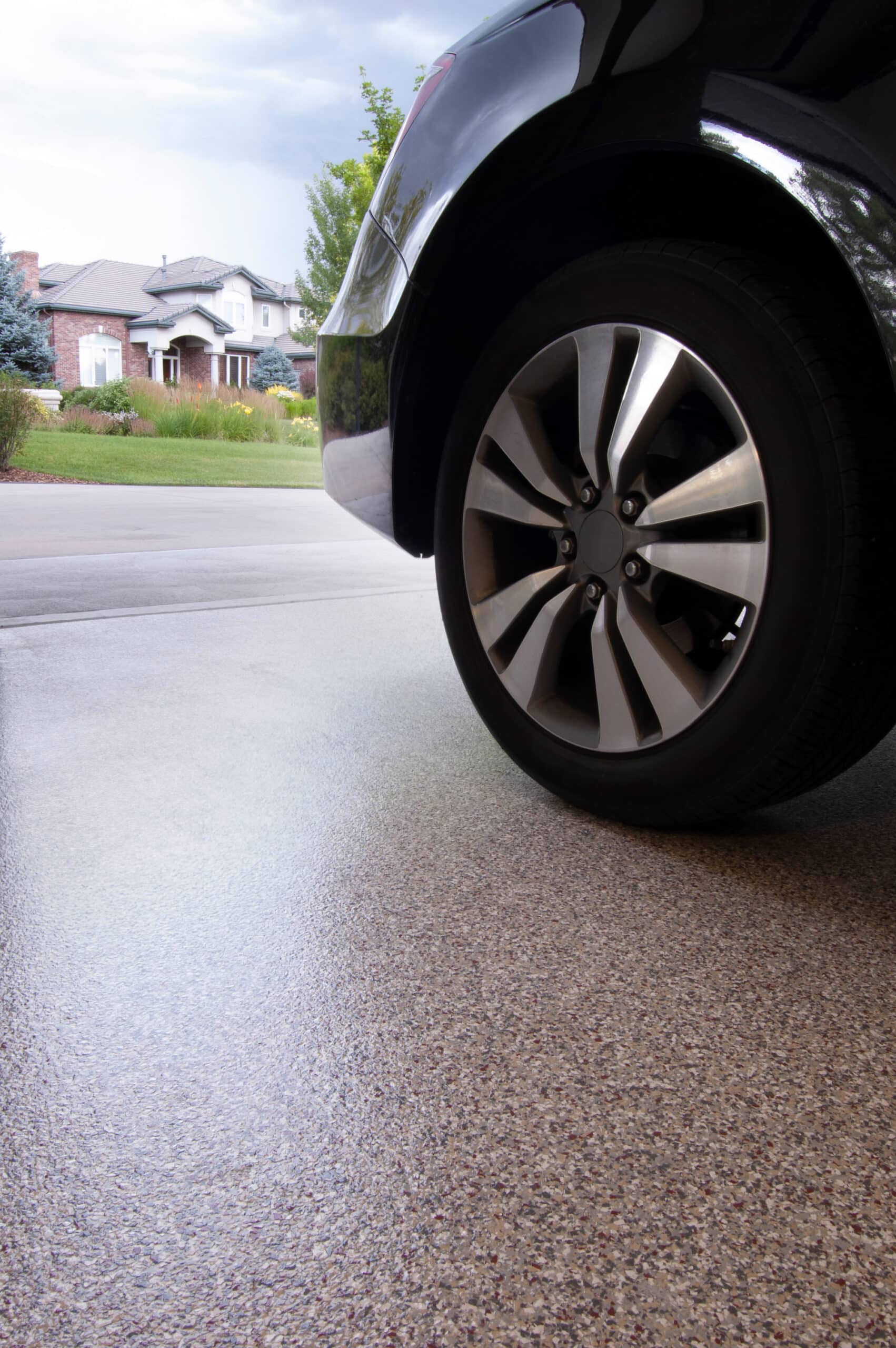 Car wheel on driveway with suburban house view.