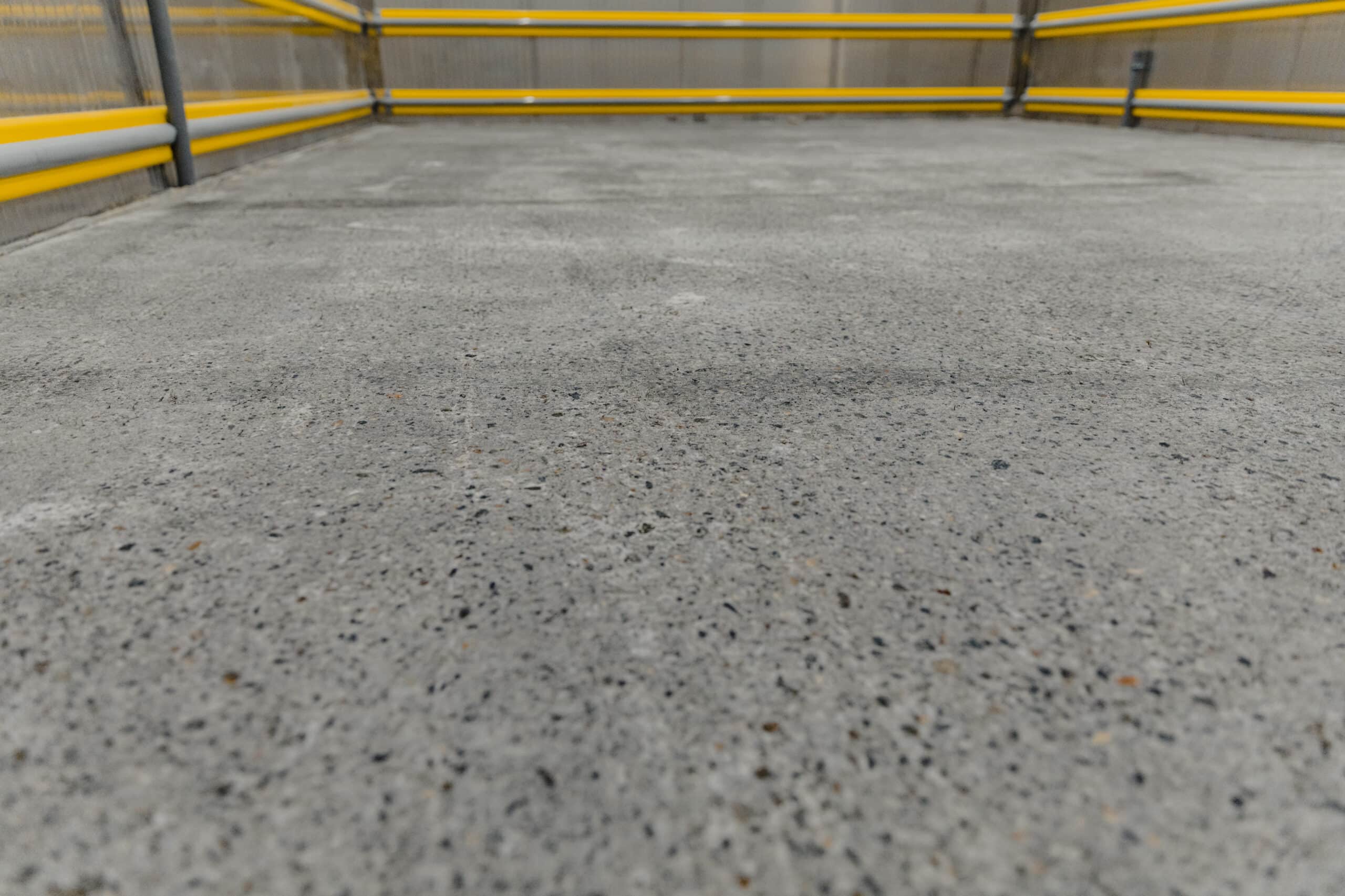 Parking lot surface with yellow safety rails.