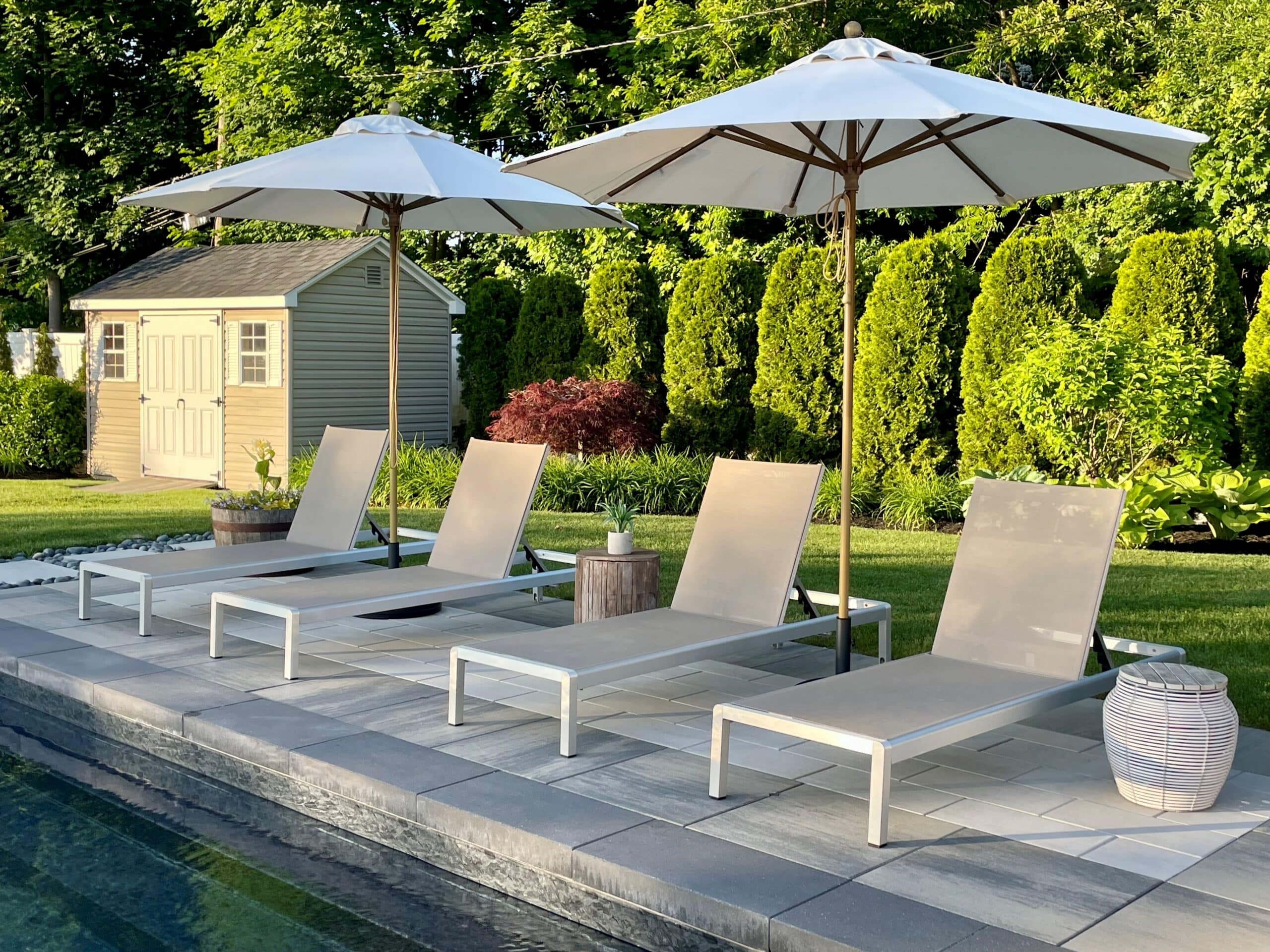 Poolside chairs and umbrellas in garden setting.