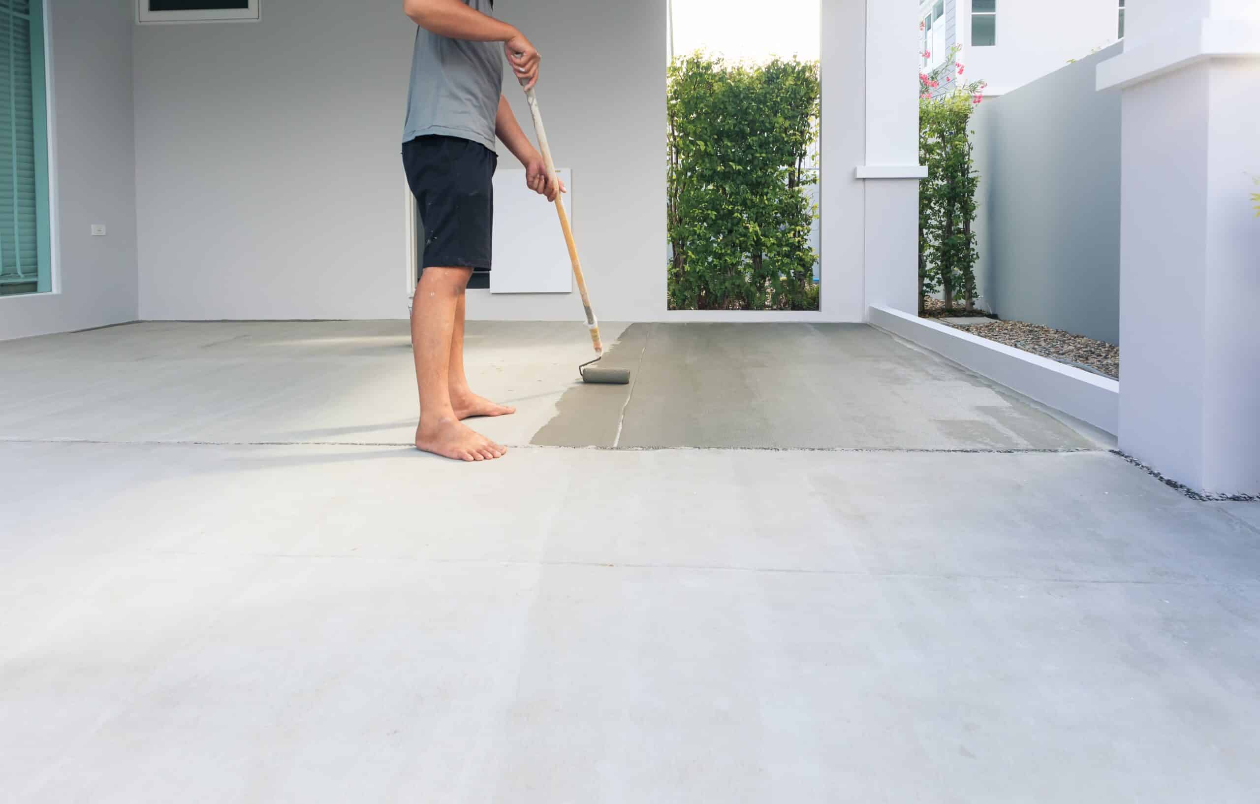 Person painting concrete porch with roller.