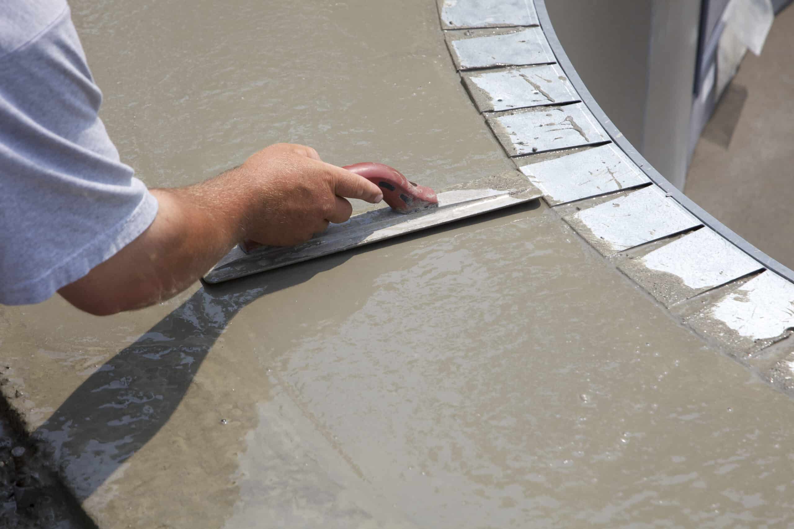 Worker smoothing wet concrete with trowel